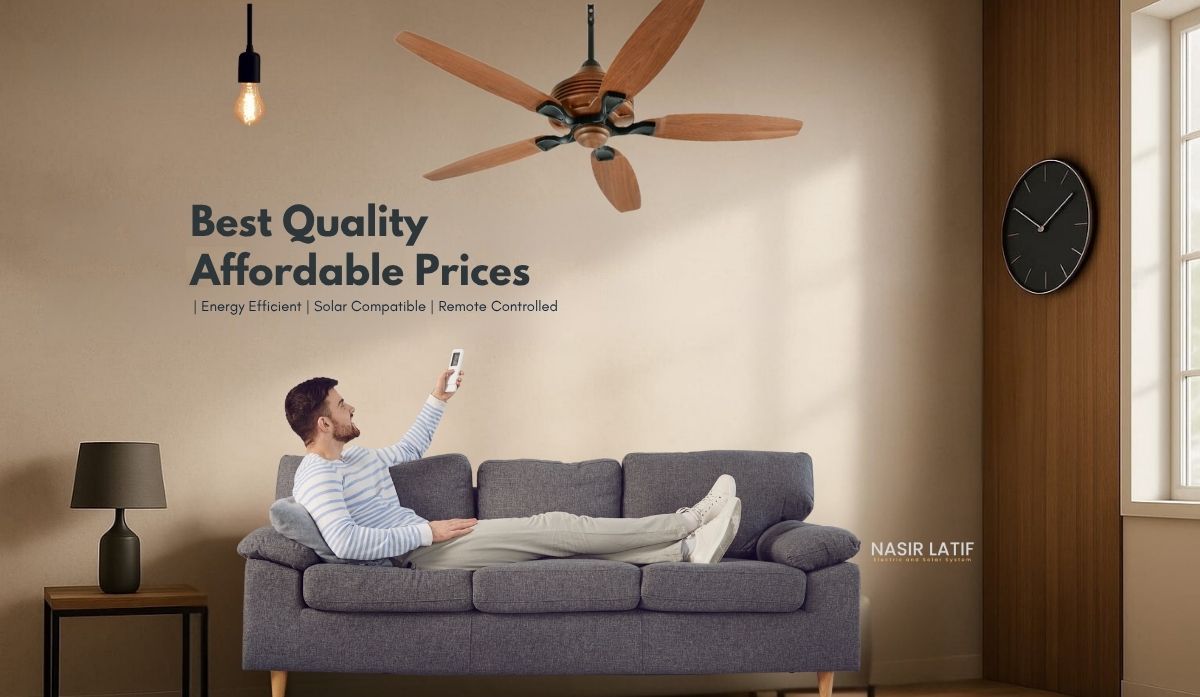 Person sitting on a couch using a remote control with a ceiling fan and wall text in the background.